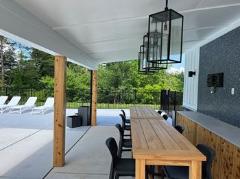 A wooden table is surrounded by chairs under a white roof.